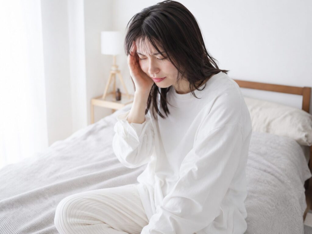 頭痛でこめかみを押さえている女性