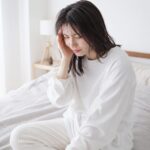 頭痛でこめかみを押さえている女性