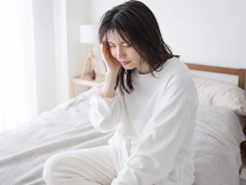 頭痛でこめかみを押さえている女性