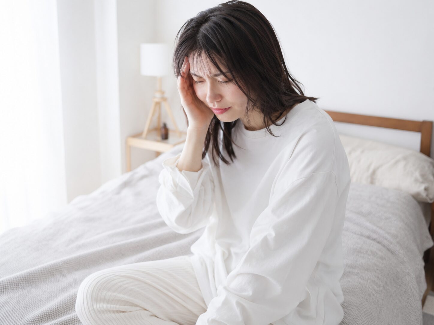 頭痛でこめかみを押さえている女性