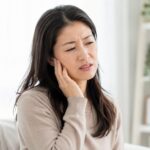 首を押さえている女性