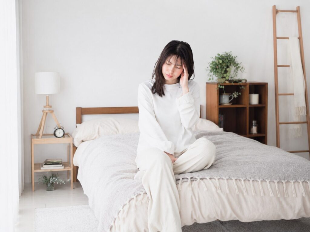 頭痛でベッドにうつむく女性