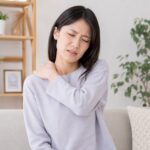 デスクワーク中に肩を押さえている女性
