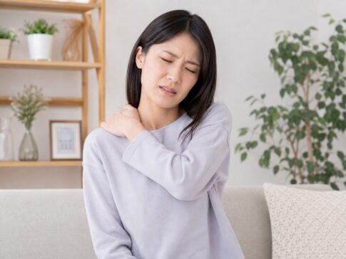 デスクワーク中に肩を押さえている女性