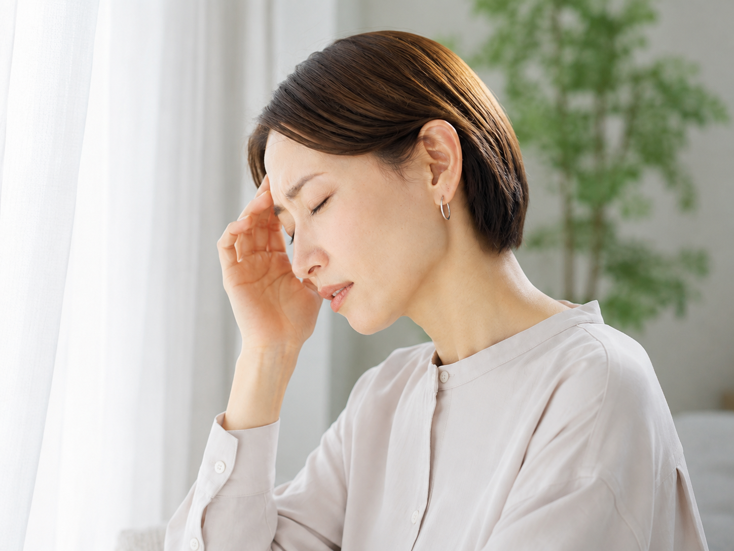 頭を押さえてつらそうにしている女性